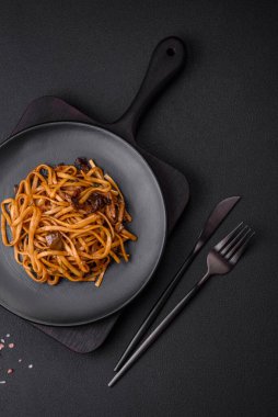 Lezzetli erişte ya da mantarlı udon, tuz, baharat ve otlar koyu beton bir zeminde seramik bir tabakta.