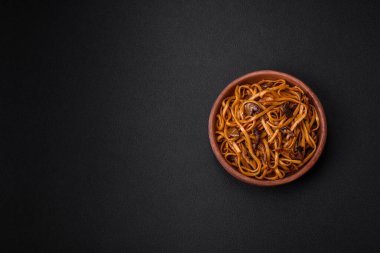 Lezzetli erişte ya da mantarlı udon, tuz, baharat ve otlar koyu beton bir zeminde seramik bir tabakta.