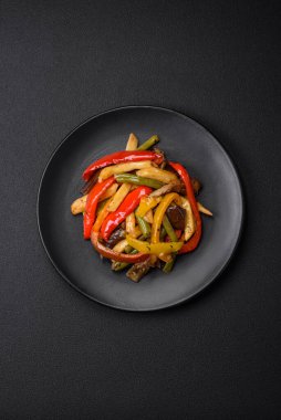 Lezzetli sebzeler biber buğulama, kuşkonmaz fasulye ve soya sosu dilimlenmiş patates koyu beton arka planda.