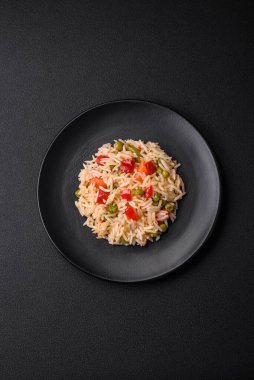 Lezzetli haşlanmış pirinç, sebzeli biber, bezelye ve kuşkonmaz fasulyesi, baharat ve otlu koyu beton arka planda.