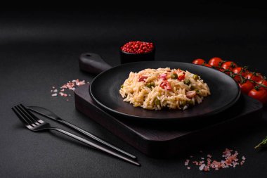 Lezzetli haşlanmış pirinç, sebzeli biber, bezelye ve kuşkonmaz fasulyesi, baharat ve otlu koyu beton arka planda.