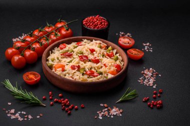 Lezzetli haşlanmış pirinç, sebzeli biber, bezelye ve kuşkonmaz fasulyesi, baharat ve otlu koyu beton arka planda.