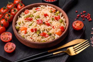 Lezzetli haşlanmış pirinç, sebzeli biber, bezelye ve kuşkonmaz fasulyesi, baharat ve otlu koyu beton arka planda.