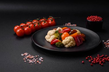 Taze vişneli domates salatası, tatlı biber, brokoli ve koyu beton arka planda tuz ve baharatlı karnabahar.