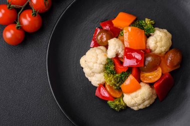 Taze vişneli domates salatası, tatlı biber, brokoli ve koyu beton arka planda tuz ve baharatlı karnabahar.