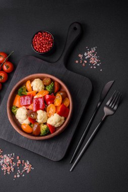 Taze vişneli domates salatası, tatlı biber, brokoli ve koyu beton arka planda tuz ve baharatlı karnabahar.