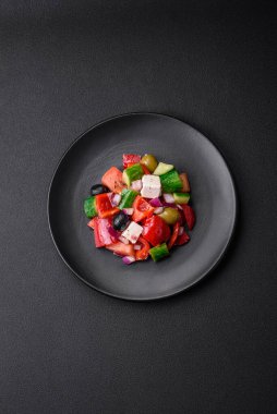 Lezzetli, feta peynirli taze Yunan salatası, zeytin, domates ve salatalık koyu beton arka planda.