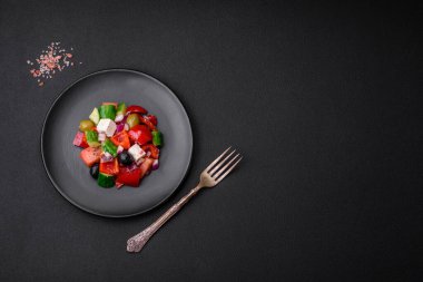 Lezzetli, feta peynirli taze Yunan salatası, zeytin, domates ve salatalık koyu beton arka planda.