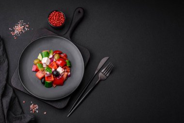 Lezzetli, feta peynirli taze Yunan salatası, zeytin, domates ve salatalık koyu beton arka planda.