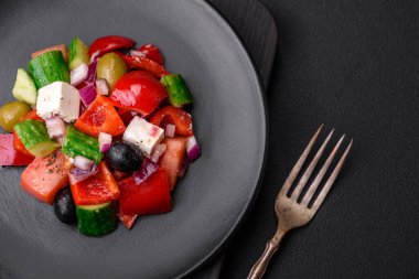 Lezzetli, feta peynirli taze Yunan salatası, zeytin, domates ve salatalık koyu beton arka planda.