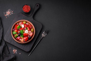 Lezzetli, feta peynirli taze Yunan salatası, zeytin, domates ve salatalık koyu beton arka planda.