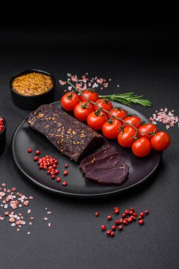 Lezzetli tütsülenmiş Ermeni basturması. Baharat ve otlarla birlikte koyu beton bir arka planda dilimlenmiş.