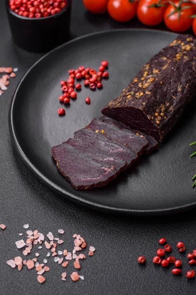 stock image Delicious smoked Armenian basturma with spices and herbs sliced on a dark concrete background