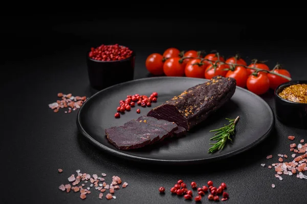 stock image Delicious smoked Armenian basturma with spices and herbs sliced on a dark concrete background