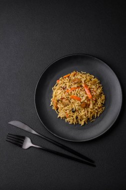 Koyu beton arka planda tavuk, havuç, böğürtlen, baharat ve bitkilerle nefis Özbek pilavı