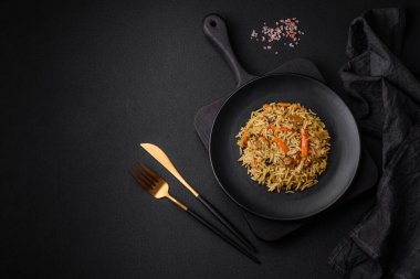 Koyu beton arka planda tavuk, havuç, böğürtlen, baharat ve bitkilerle nefis Özbek pilavı