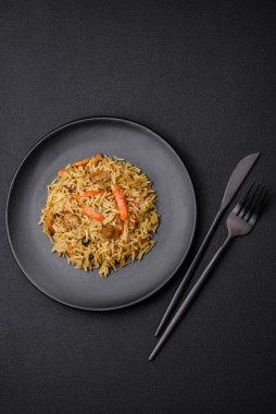 Koyu beton arka planda tavuk, havuç, böğürtlen, baharat ve bitkilerle nefis Özbek pilavı