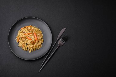 Koyu beton arka planda tavuk, havuç, böğürtlen, baharat ve bitkilerle nefis Özbek pilavı