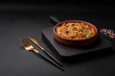 Koyu beton arka planda tavuk, havuç, böğürtlen, baharat ve bitkilerle nefis Özbek pilavı