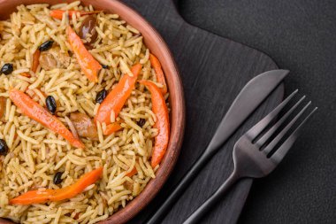 Delicious Uzbek pilaf with chicken, carrots, barberry, spices and herbs on a dark concrete background clipart
