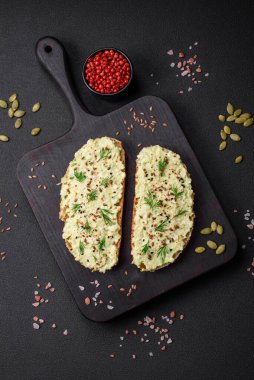 Avokado macunu, yumurta, krem peynir, tuz, baharat ve çimento kaplı bir masada ızgara tost.