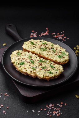 Avokado macunu, yumurta, krem peynir, tuz, baharat ve çimento kaplı bir masada ızgara tost.