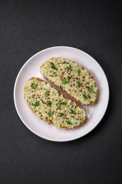 Avokado macunu, yumurta, krem peynir, tuz, baharat ve çimento kaplı bir masada ızgara tost.