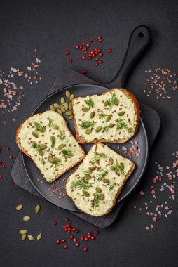 Avokado macunu, yumurta, krem peynir, tuz, baharat ve çimento kaplı bir masada ızgara tost.