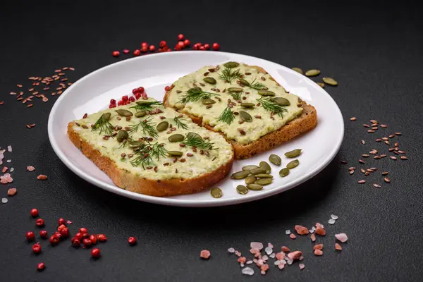 Avokado macunu, yumurta, krem peynir, tuz, baharat ve çimento kaplı bir masada ızgara tost.