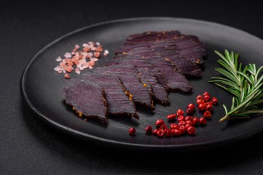 Lezzetli kurutulmuş biftek ya da at eti. Baharatlı kurutulmuş et ve koyu beton arka planda tuz.