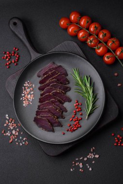 Lezzetli kurutulmuş biftek ya da at eti. Baharatlı kurutulmuş et ve koyu beton arka planda tuz.