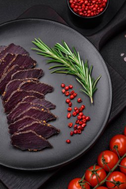 Lezzetli kurutulmuş biftek ya da at eti. Baharatlı kurutulmuş et ve koyu beton arka planda tuz.