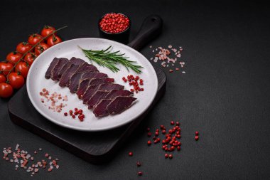 Lezzetli kurutulmuş biftek ya da at eti. Baharatlı kurutulmuş et ve koyu beton arka planda tuz.