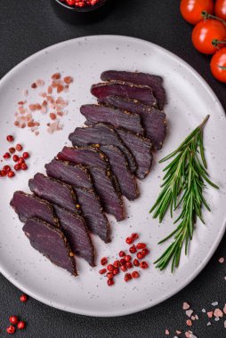 Lezzetli kurutulmuş biftek ya da at eti. Baharatlı kurutulmuş et ve koyu beton arka planda tuz.