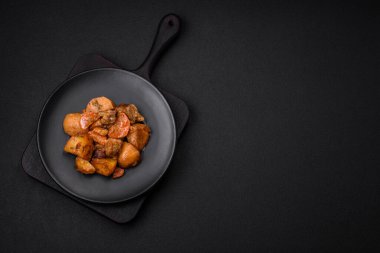 Lezzetli taze domuz etli yahni ya da koyu beton arka planda patates, havuç, baharat ve otlarla biftek.