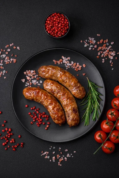 stock image Delicious fried grilled sausages with salt, spices and herbs on a dark concrete background