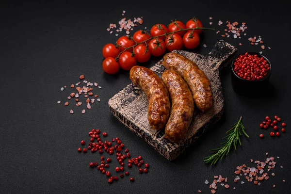 stock image Delicious fried grilled sausages with salt, spices and herbs on a dark concrete background