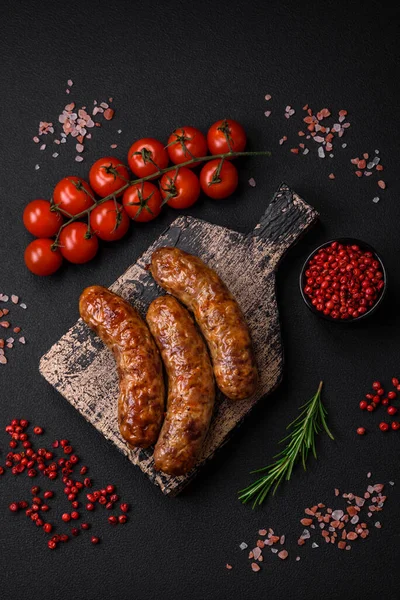 stock image Delicious fried grilled sausages with salt, spices and herbs on a dark concrete background