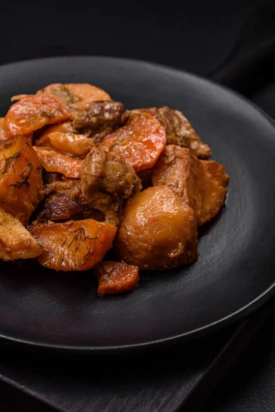 Lezzetli taze domuz etli yahni ya da koyu beton arka planda patates, havuç, baharat ve otlarla biftek.