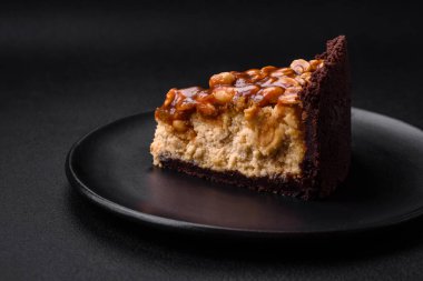 Lezzetli taze cheesecake keki ya da koyu beton arka planda seramik tabakta kremalı ve fındıklı snickers.