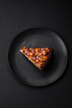 Lezzetli taze cheesecake keki ya da koyu beton arka planda seramik tabakta kremalı ve fındıklı snickers.