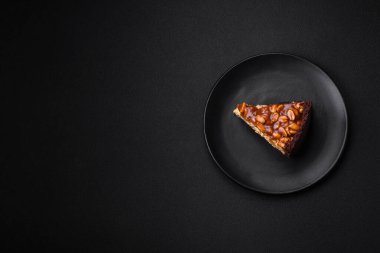 Lezzetli taze cheesecake keki ya da koyu beton arka planda seramik tabakta kremalı ve fındıklı snickers.