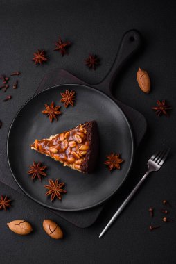 Lezzetli taze cheesecake keki ya da koyu beton arka planda seramik tabakta kremalı ve fındıklı snickers.