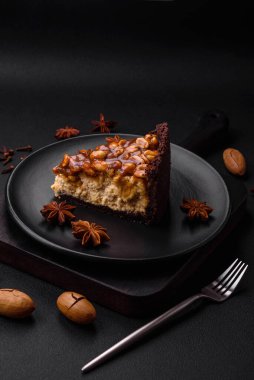 Lezzetli taze cheesecake keki ya da koyu beton arka planda seramik tabakta kremalı ve fındıklı snickers.