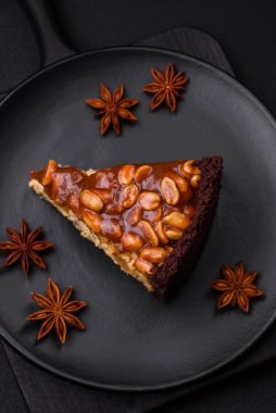 Lezzetli taze cheesecake keki ya da koyu beton arka planda seramik tabakta kremalı ve fındıklı snickers.