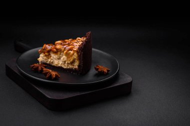 Lezzetli taze cheesecake keki ya da koyu beton arka planda seramik tabakta kremalı ve fındıklı snickers.