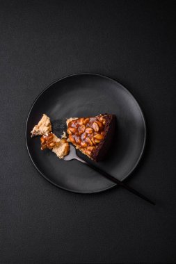 Lezzetli taze cheesecake keki ya da koyu beton arka planda seramik tabakta kremalı ve fındıklı snickers.