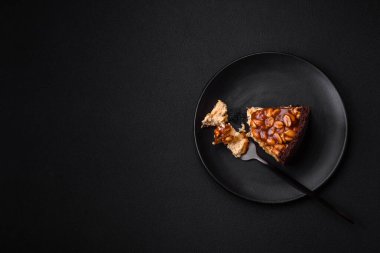 Lezzetli taze cheesecake keki ya da koyu beton arka planda seramik tabakta kremalı ve fındıklı snickers.