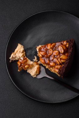 Lezzetli taze cheesecake keki ya da koyu beton arka planda seramik tabakta kremalı ve fındıklı snickers.