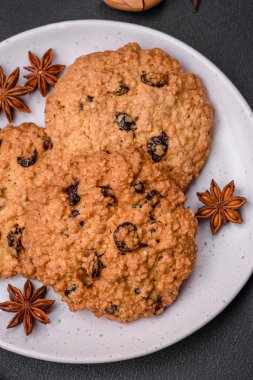 Koyu beton zemin üzerinde lezzetli pişmiş yulaflı kuru üzümlü kurabiyeler. Kahvaltıda tatlı.